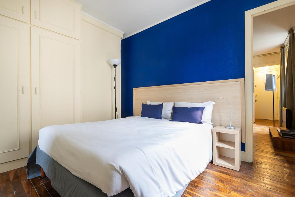 a bedroom with a large bed with a blue wall at Smart Inn Fontainebleau Centre- Appartement 1 chambre in Fontainebleau