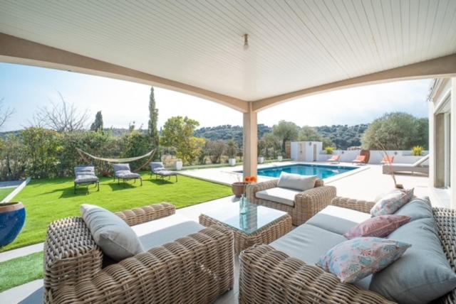 eine Terrasse mit Korbmöbeln und einem Pool in der Unterkunft Villa Noham in Vivès