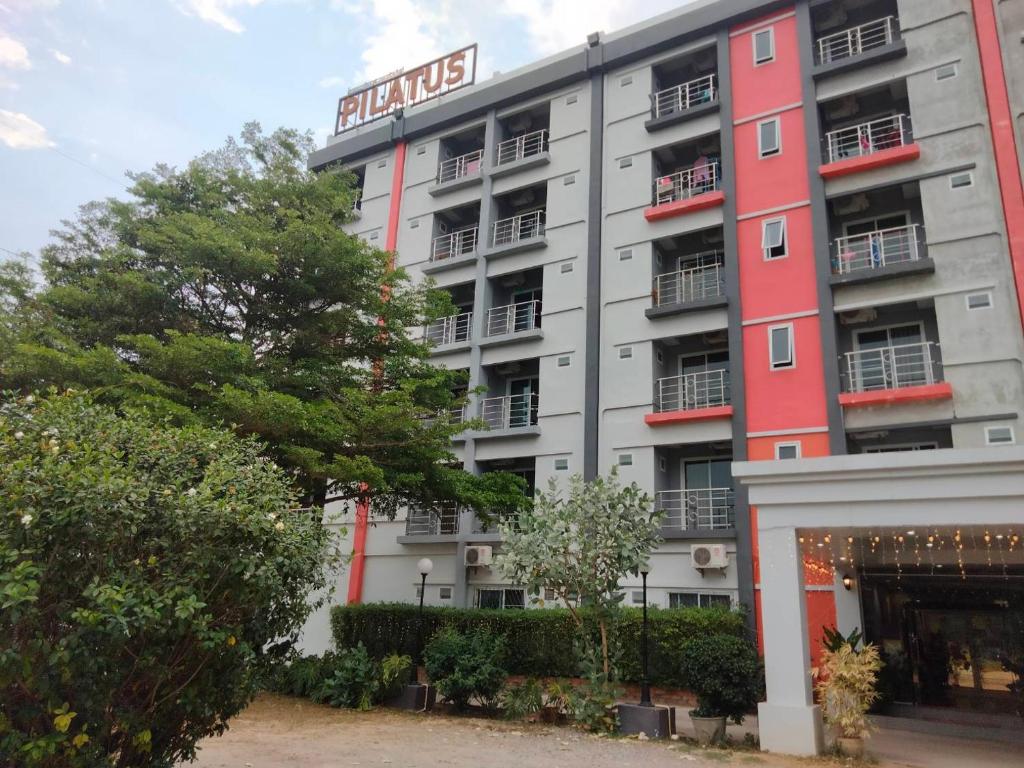a hotel with a red and white building at Pilatus Apartment in Loei
