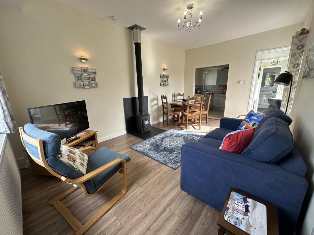 a living room with a blue couch and a fireplace at Ty'r Ardd - An immaculate 2 bedroom bungalow close to the beach in Pendine