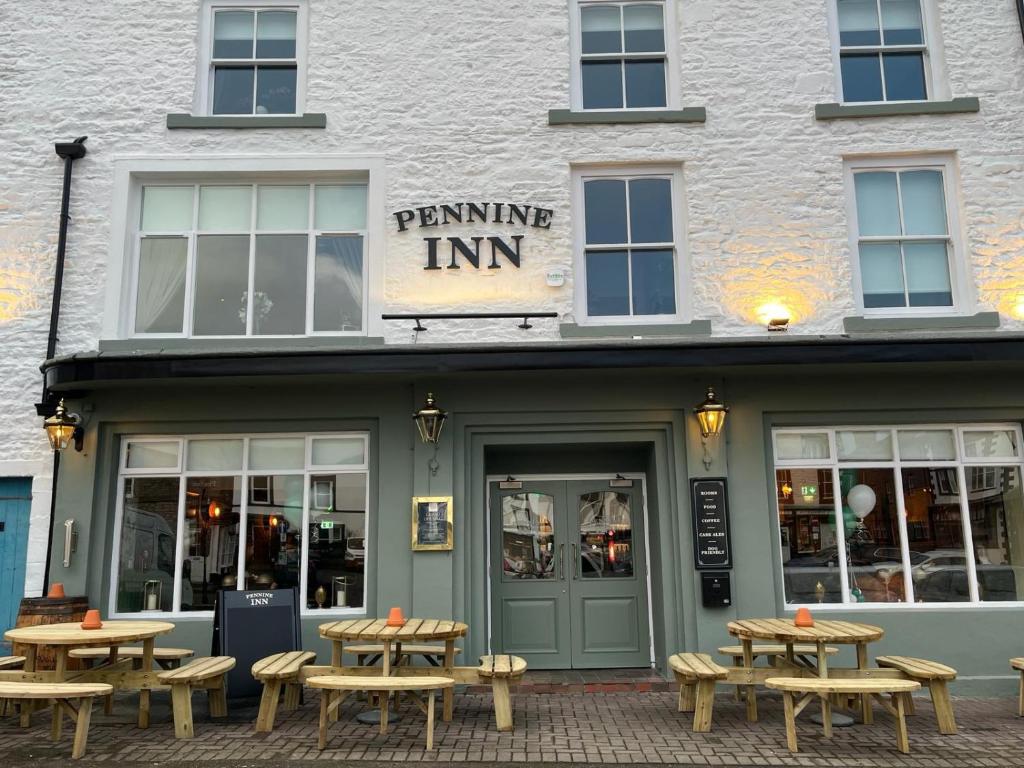 um edifício com mesas de piquenique em frente em The Pennine Inn em Kirkby Stephen