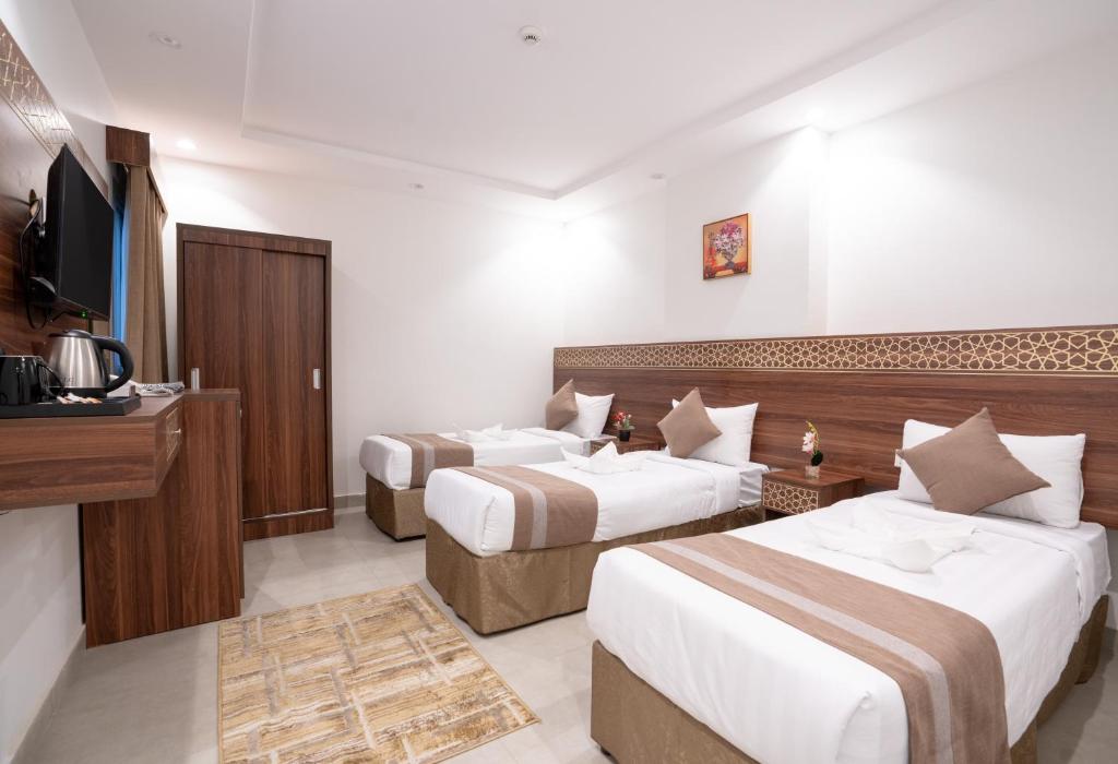 Cette chambre comprend deux lits et une télévision. dans l'établissement فندق سيف بلص من سما, à La Mecque