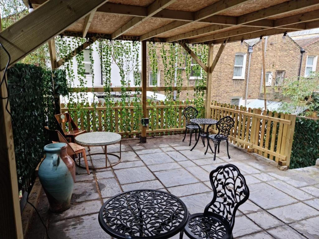 acovered patio with tables and chairs and a table at SureBillionaire Home Deluxe Queen Studio in London