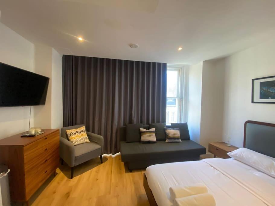 um quarto de hotel com uma cama, um sofá e uma televisão em Sleep6 Flat at Iconic Piccadilly circus VR6 em Londres