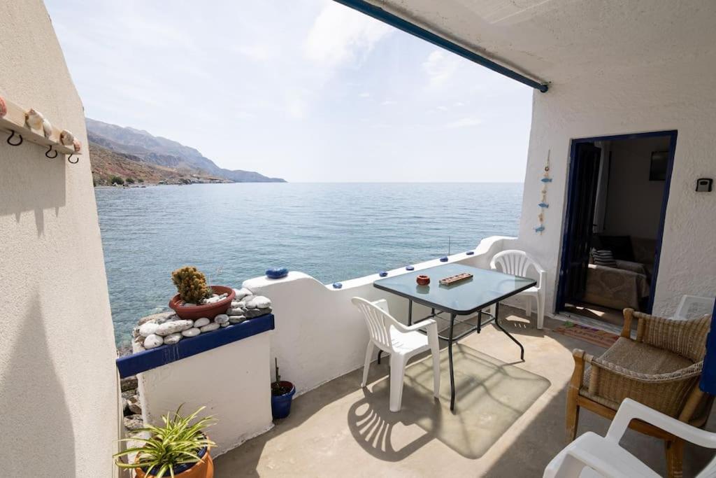 balcón con mesa y vistas al agua en Beachfront Lovely Small House on the Sea en Paránimfoi