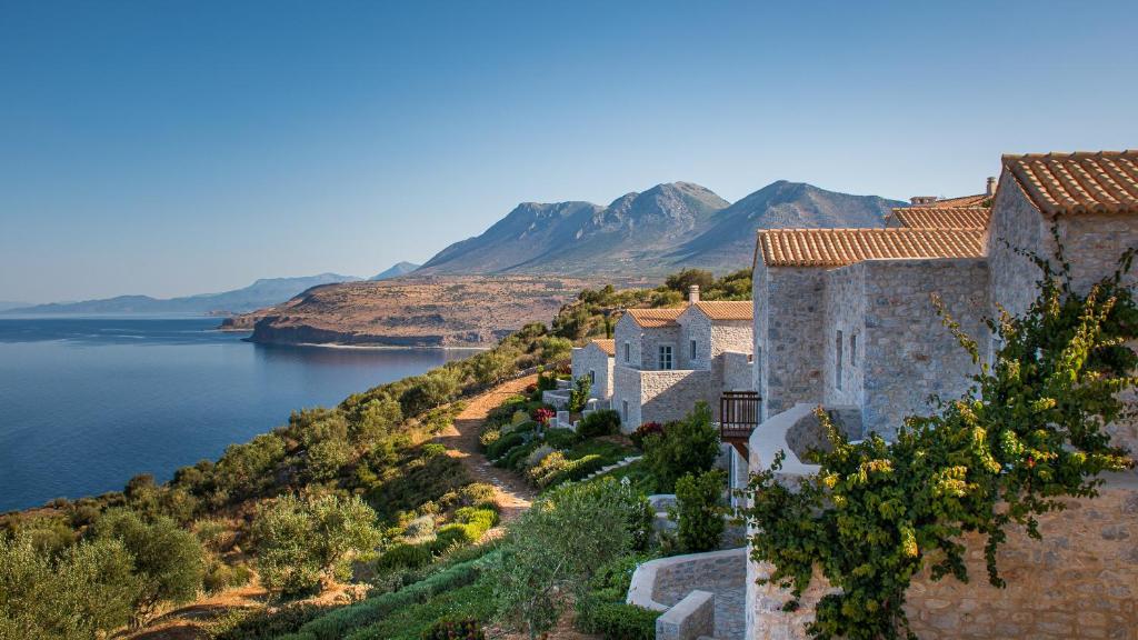 an old building on a hill next to a body of water at BASSA MAINA Villas & Suites in Areopoli