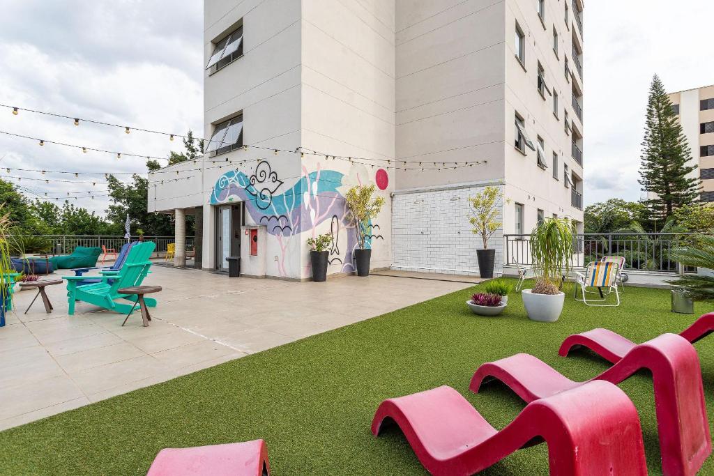 ein Gebäude mit einem Hof mit rosa Bänken darauf in der Unterkunft Caza Noz by Viva - Apartamentos com ótima estrutura e área comum próximo à USP e Butantã in São Paulo