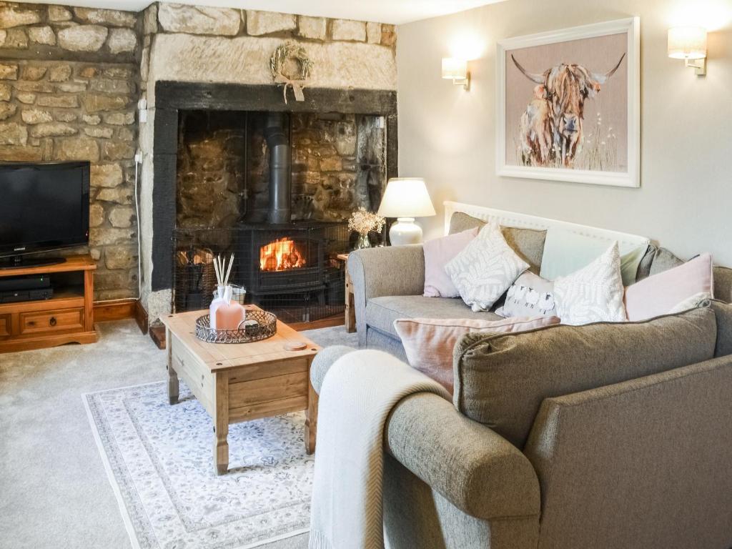 sala de estar con sofá y chimenea en Middles Cottage en West Woodburn