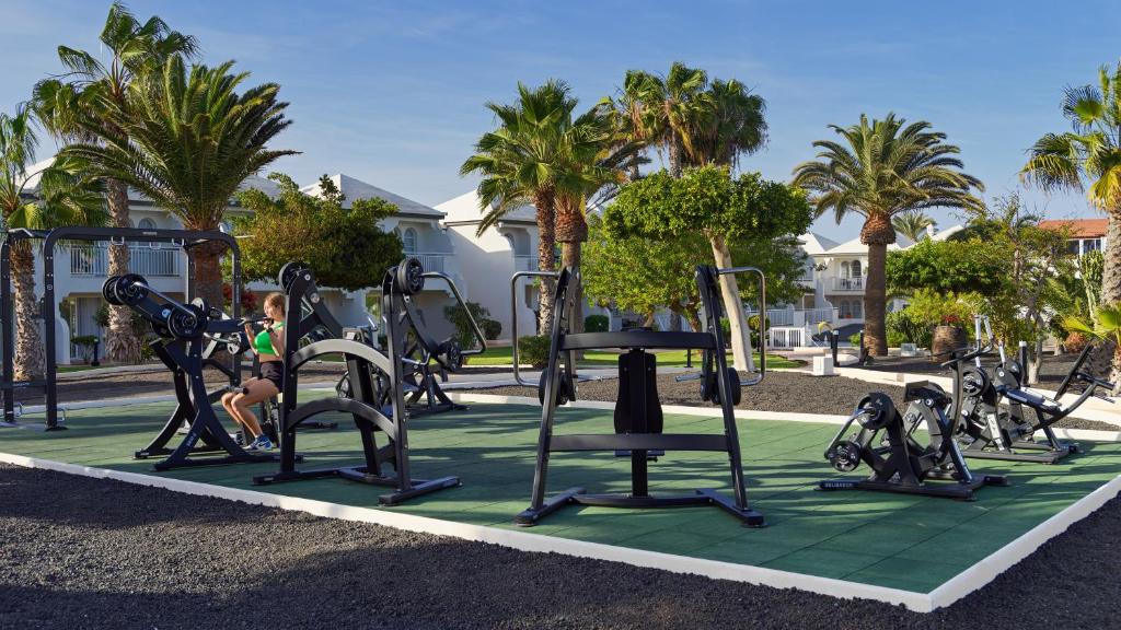 a group of exercise equipment in a park with palm trees at H10 Ocean Suites in Corralejo