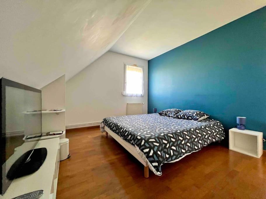 Un dormitorio con una cama y una pared azul. en A la campagne chez l'habitant, en Germainville