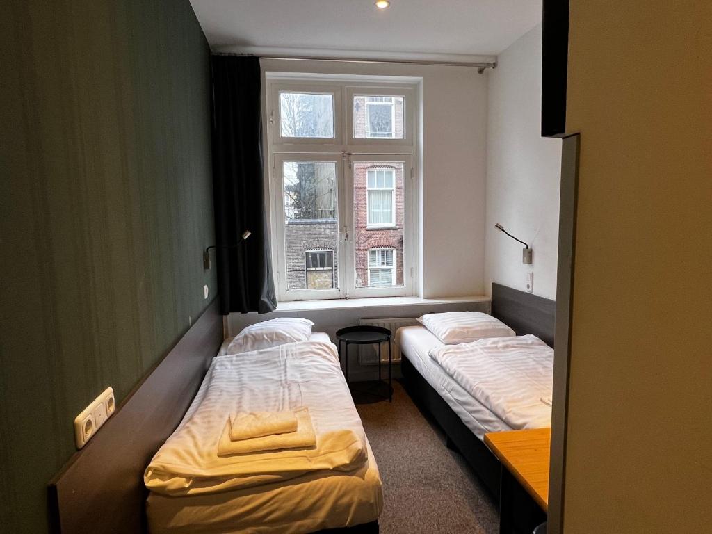 2 camas en una habitación pequeña con ventana en Budget Trianon Hotel en Ámsterdam