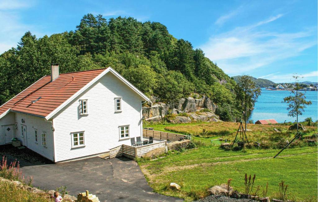 a white house with a red roof next to the water at Lovely Home In Farsund With Wi-Fi in Farsund