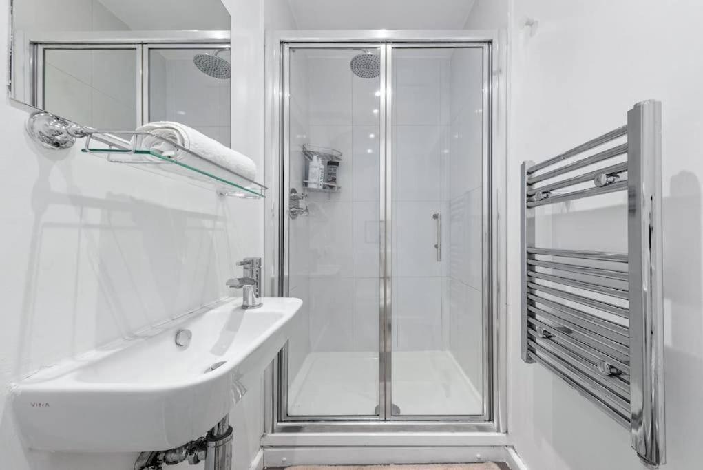 y baño blanco con lavabo y ducha. en Central London Gem 1 BR Flat Piccadilly Circus VR8, en Londres