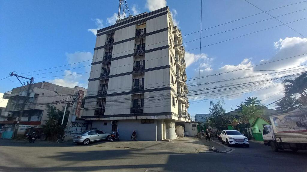 un grand bâtiment blanc avec des voitures garées devant lui dans l'établissement OYO 1066 Dorotello Apartelle, à Manille