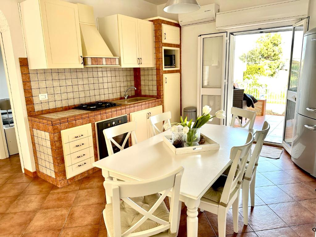 una cucina con tavolo bianco e sedie bianche di Casa Sunshine 2.0 - Vacanze al mare a Punta Braccetto