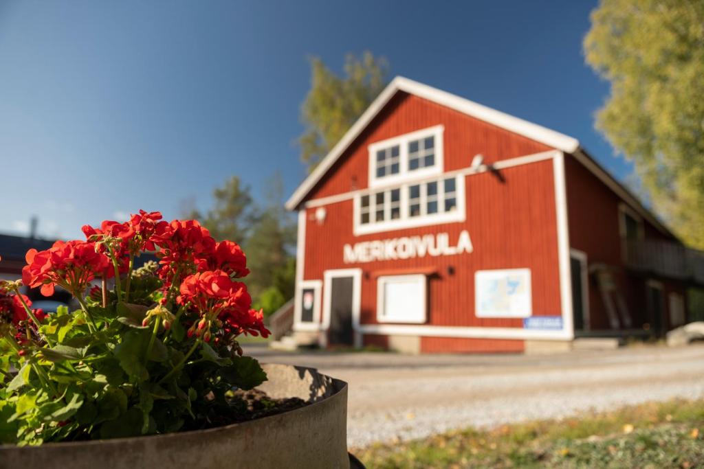 a red barn with a pot of flowers in front of it at Fishing and holiday village Merikoivula in Uusikaupunki