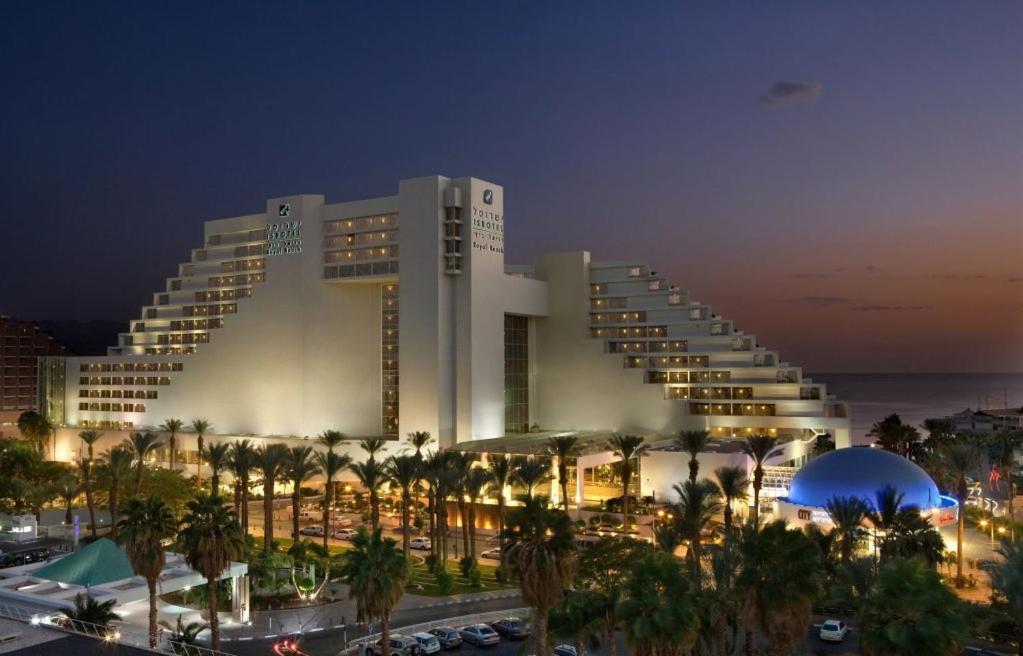 a large building with palm trees in front of it at Royal Beach eilat in Eilat