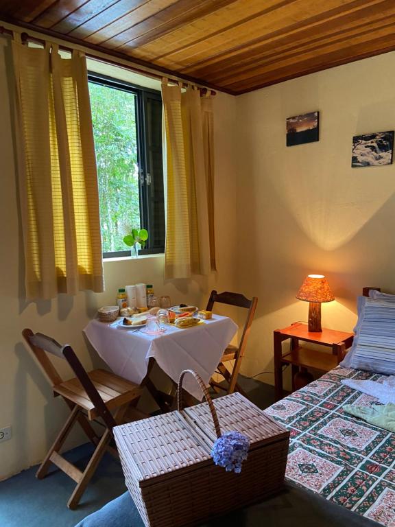 カンポス・ド・ジョルドンにあるAromas da Serra IIのテーブルと椅子、窓が備わる客室です。