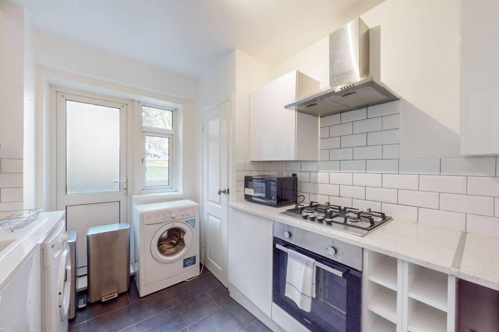 una cocina blanca con lavadora y secadora. en Cozy 3 bedroom apartment in Brixton, en Londres