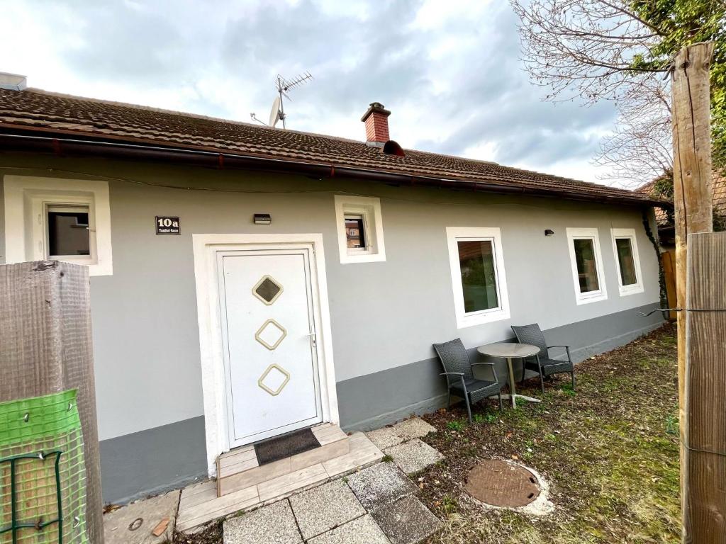 une maison blanche avec une porte blanche et une table dans l'établissement Häuschen für Monteure, Autobahn, à Bruck an der Mur