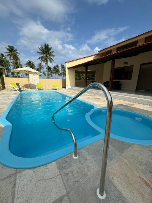 uma grande piscina azul com corrimão de metal em Casa aconchegante em Guadalupe/PE em Sirinhaém