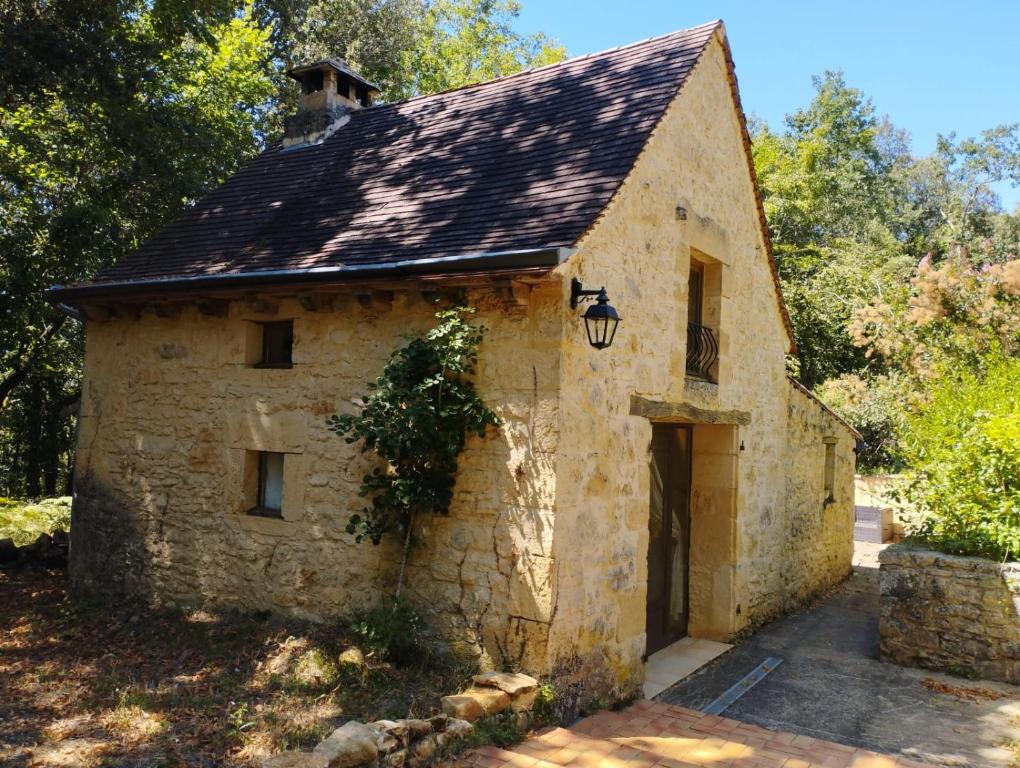 ein altes Steingebäude mit schwarzem Dach in der Unterkunft Le Pas de la Lande in Groléjac