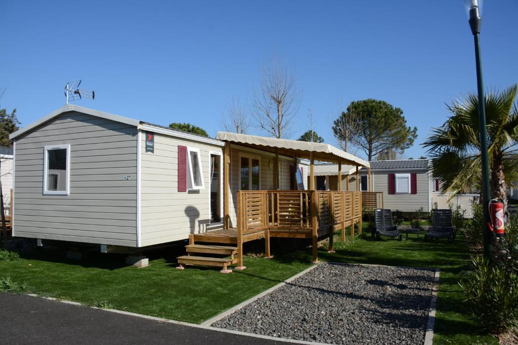 une petite maison avec un porche et une terrasse dans l'établissement Mobil home - Clim, LV, LL, TV - Camping LA CARABASSE 4 étoiles - MH-A004, à Vias