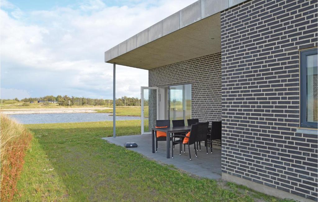 a patio with a table and chairs next to a building at Gorgeous Home In Ringkbing With House A Panoramic View in Søndervig