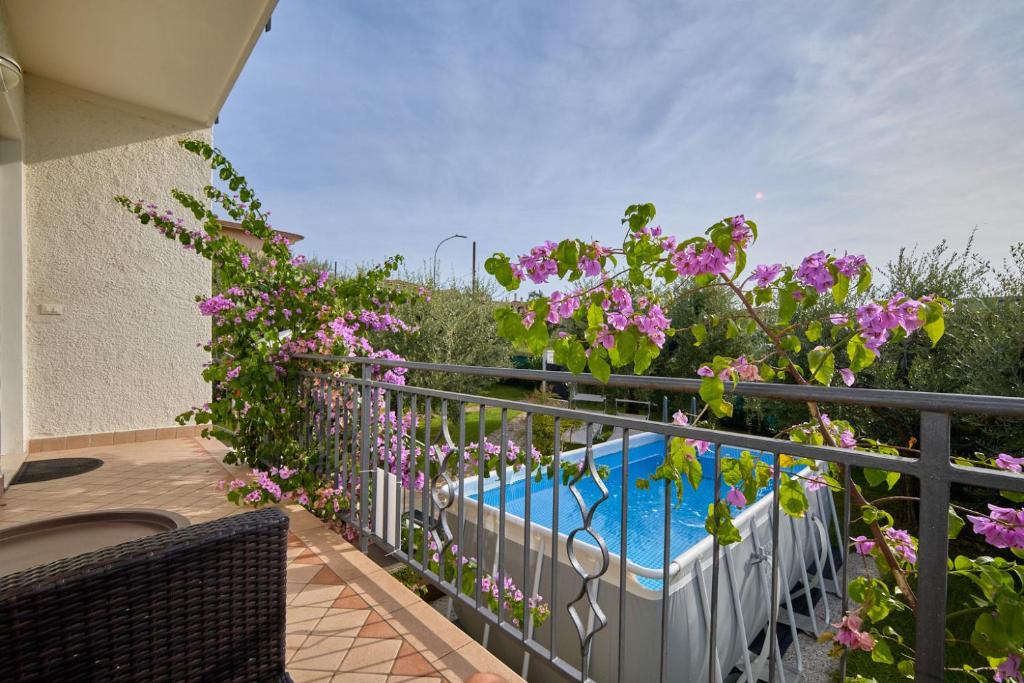 un balcón con flores púrpuras y una piscina en App. Mimosa Minerva Holiday Home, en Manerba del Garda