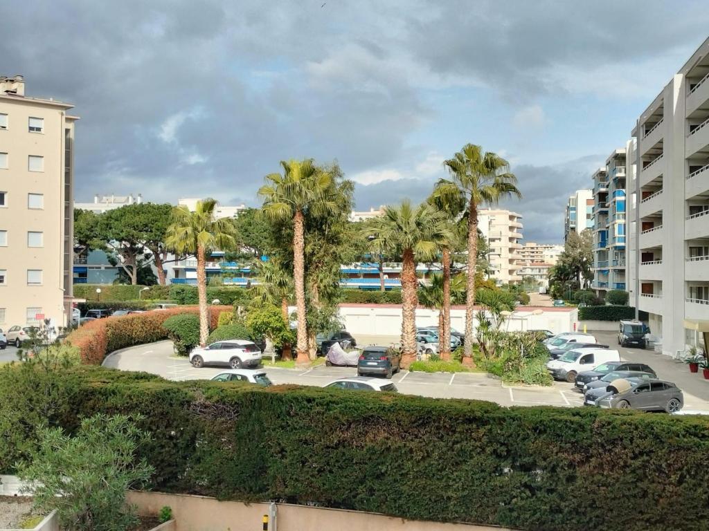 a view of a parking lot with palm trees and buildings at Tiercé Hotel in Cagnes-sur-Mer