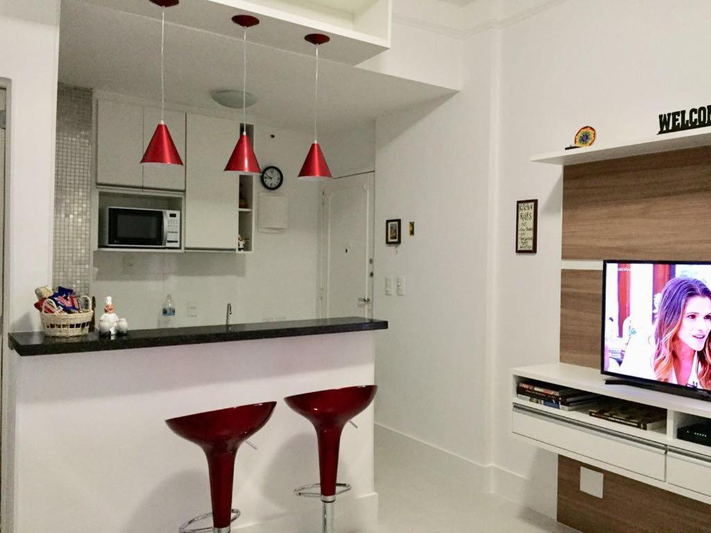 a kitchen with two red stools and a tv at Real Apartments 091 - Excelente Studio em Copacabana próximo da Praia e do Metrô in Rio de Janeiro
