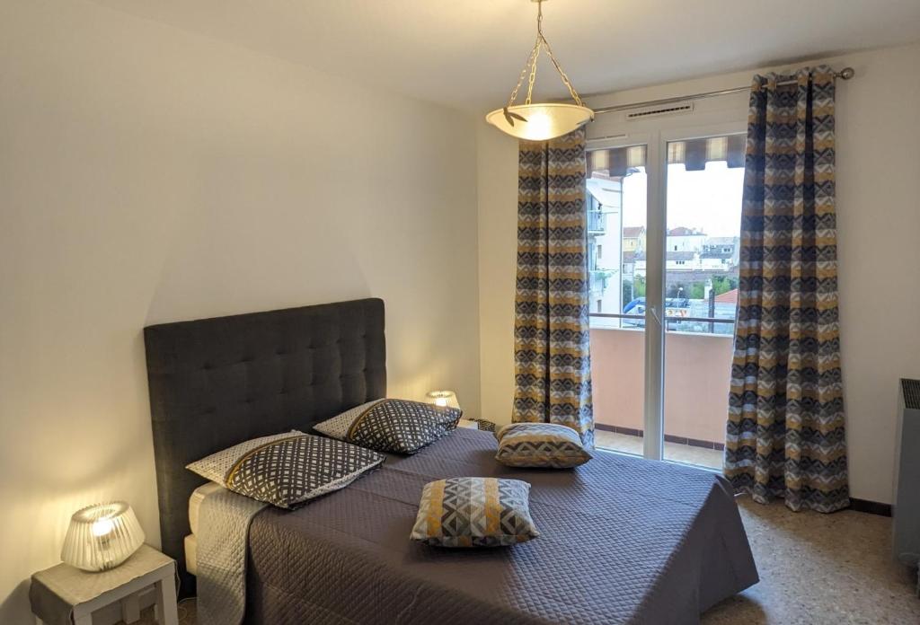 une chambre avec un lit avec des oreillers et une fenêtre dans l'établissement Golfe Juan grand 2 pièces proche plage et Cannes, à Vallauris