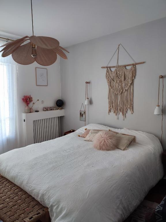 une chambre avec un grand lit blanc avec des oreillers roses dans l'établissement À 15 minutes de Paris, bel appartement au calme, à Colombes