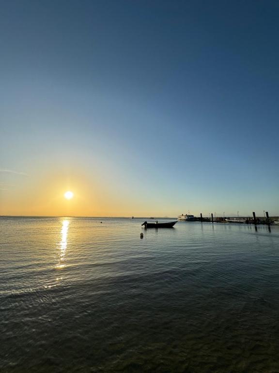 a sunset over the ocean with a boat in the water at Bela Vista - Casa Beira Mar in Paranaguá