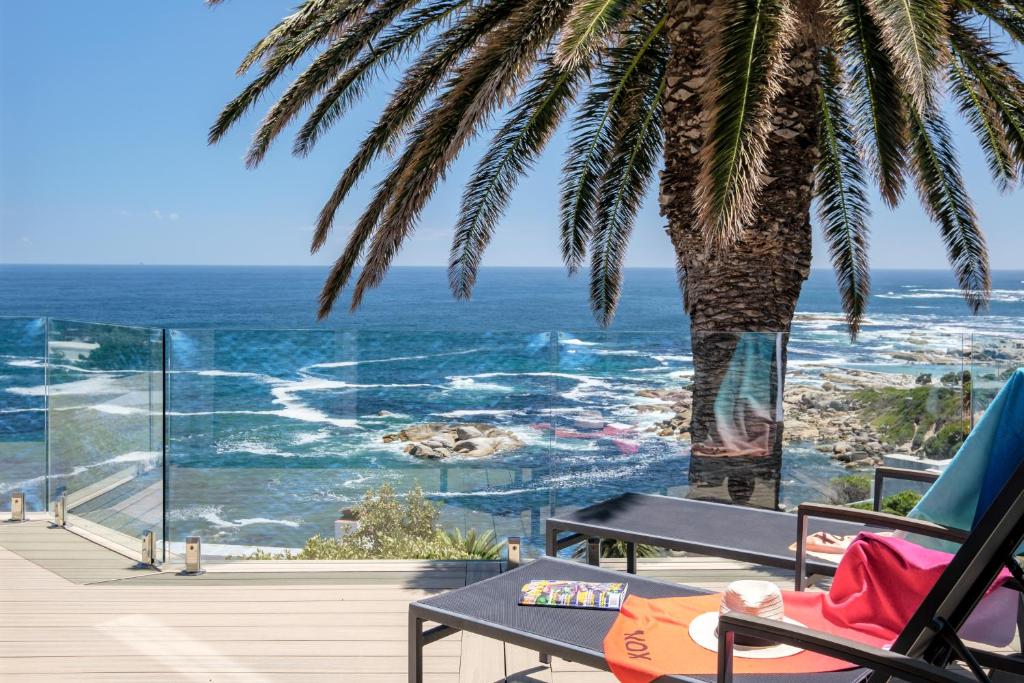 a view of the ocean from a deck with a palm tree at Houghton Steps in Cape Town