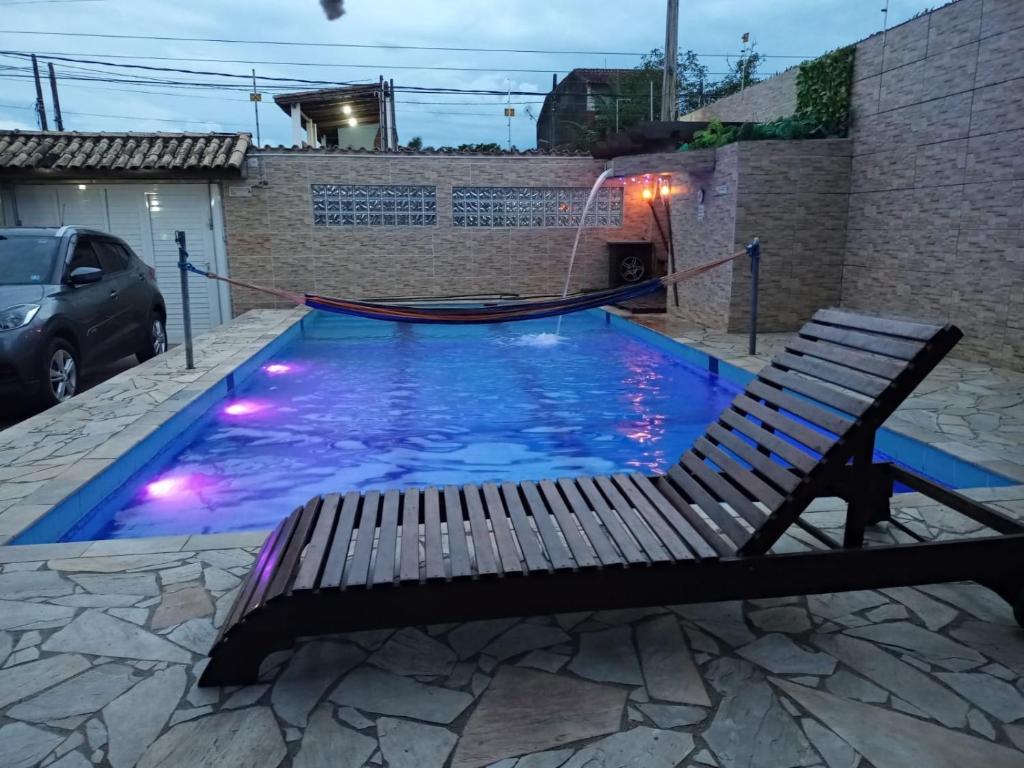 a swimming pool with a bench and a gazebo at Hostel Canto da Alegria in Itanhaém