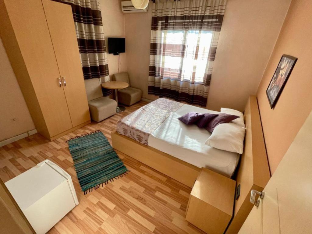 um pequeno quarto com uma cama e uma janela em Hotel Algo em Tirana