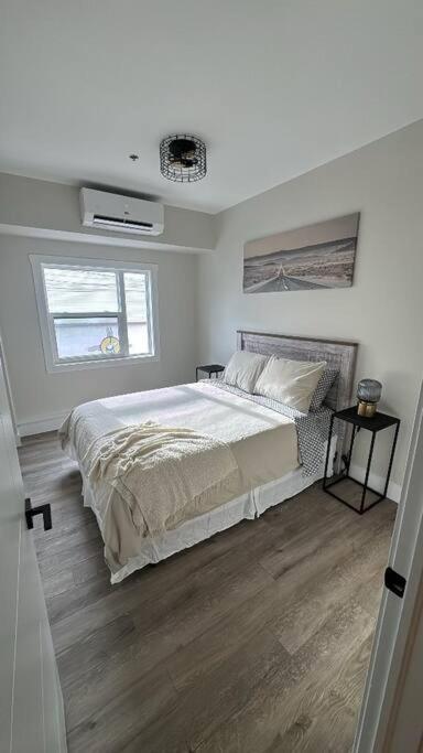 a white bedroom with a bed and a window at Modern One Bedroom Suite in Halifax