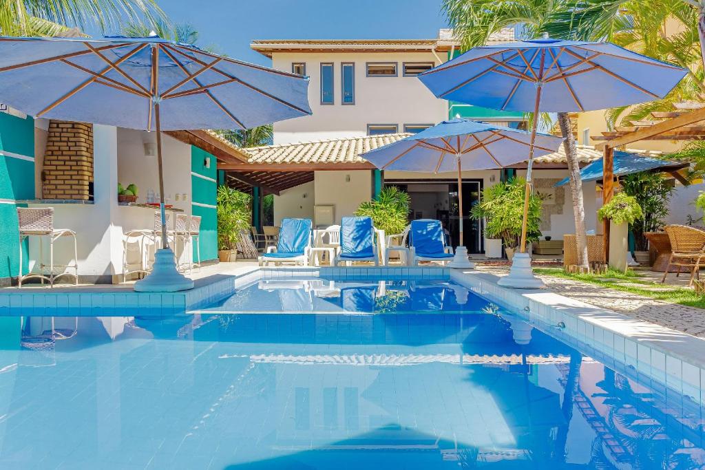 グアラジュバにあるGB19 Casa 7 Quartos a 50m da Praia - Guarajubaの青い椅子とパラソルのあるプール