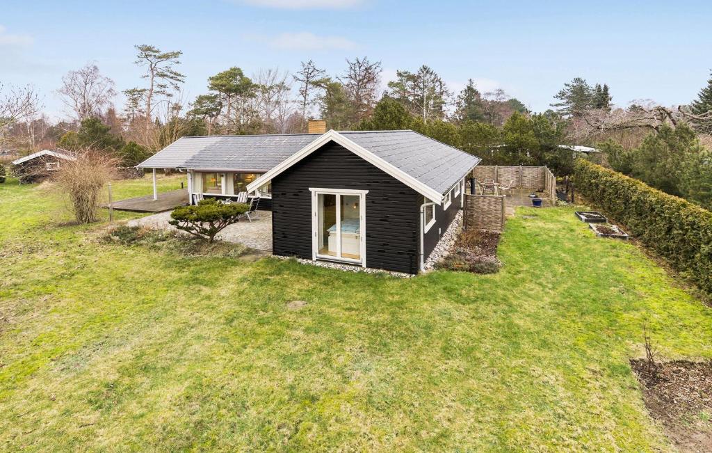 una pequeña casa negra en un campo de hierba en Beautiful Home In Melby With Kitchen, en Melby