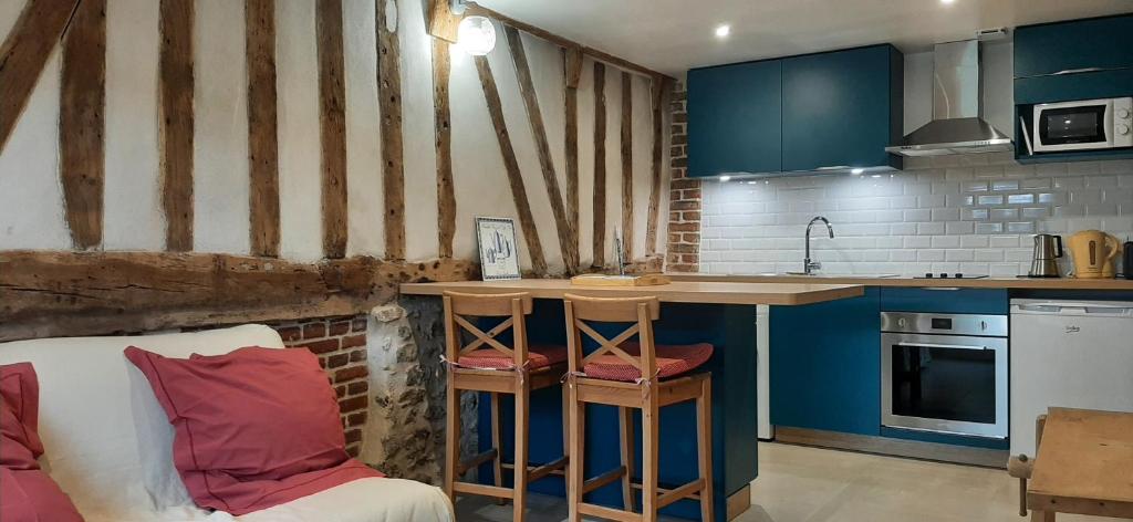 una cocina con armarios azules y una barra con taburetes en Le Thuit - F2 Plain pied tout équipé à la ferme, en Charleval