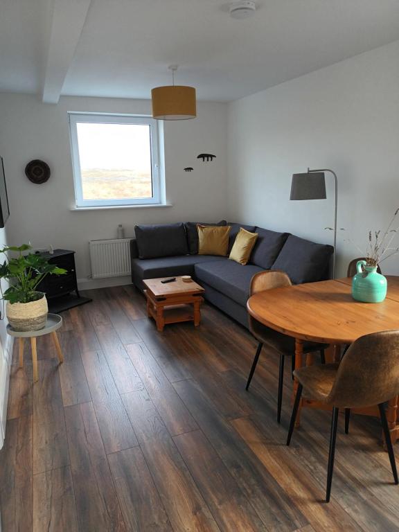 sala de estar con sofá azul y mesa en Connemara Lake View Apartment, en Camus Eighter