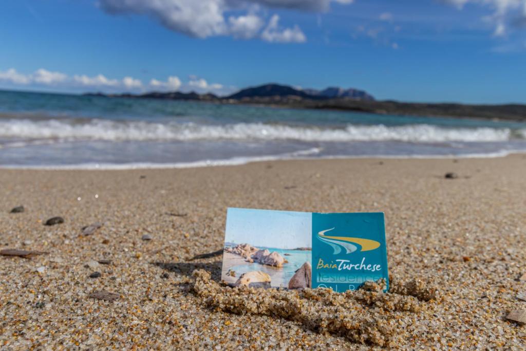 un livre dans le sable sur une plage dans l'établissement Baia Turchese Olbia, à Olbia