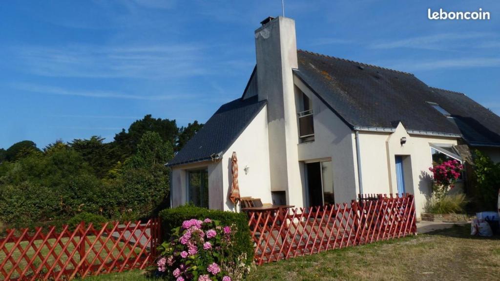 une petite maison blanche avec une clôture rouge dans l'établissement La palette - Maison vue sur mer, à Saint-Gildas-de-Rhuys