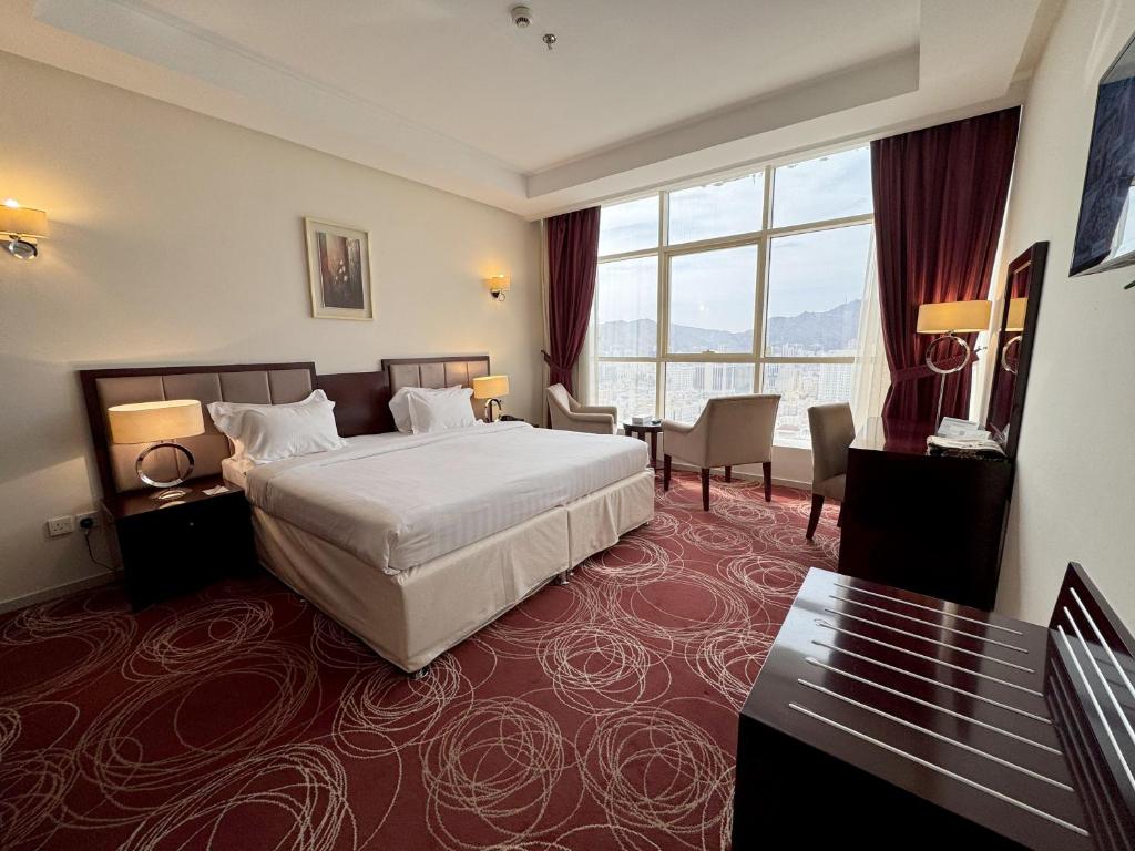 um quarto de hotel com uma cama e uma grande janela em Al Rayyan Towers 1 em Meca
