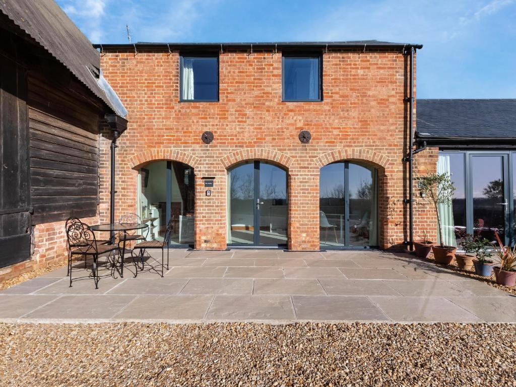 a brick building with a table and chairs on a patio at The Hollow At The Linhay in Sawtry