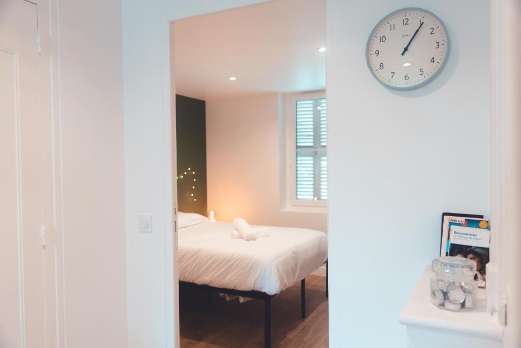 une chambre avec un lit et une horloge au mur dans l'établissement Agréable T2 - Jardin botanique, à Tours