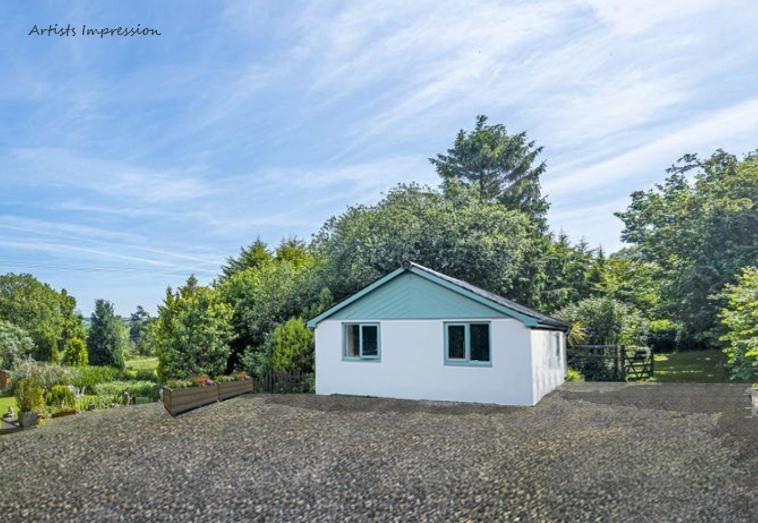 a small white shed sitting on top of a gravel lot at Deer View in Bishops Tawton