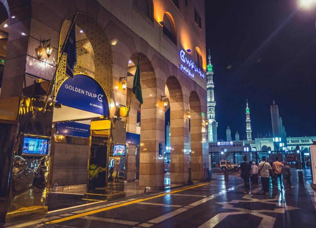 a city street at night with a mosque in the background at Golden Tulip Al-Zahabi in Medina