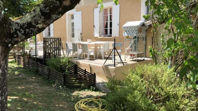 une maison avec un patio avec une table et des chaises dans l'établissement LA FERME DU PAVILLON, à Sainte-Croix-du-Mont